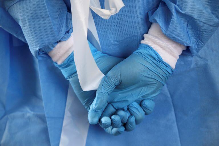 A nurse, wearing rubber, waits gloves for the city's coronavirus testing site to open next to Citizens Bank Park in South Philadelphia on Friday, March 20, 2020. The site, which opened Friday afternoon, is the first city-run location where people can be swabbed to determine if they have the coronavirus. At the time of opening, it was only for people with symptoms who are over 50 and healthcare workers with symptoms. (Tim Tai/The Philadelphia Inquirer via AP)