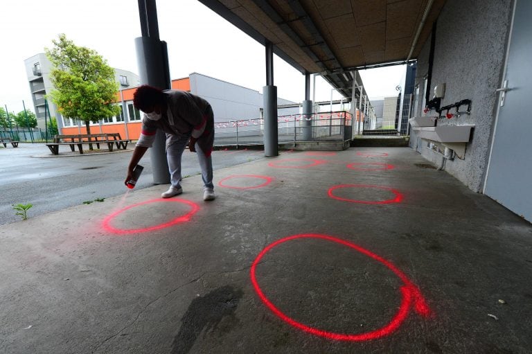 Una empleada de la escuela pinta círculos para que los niños mantengan distancia (Foto: AFP)