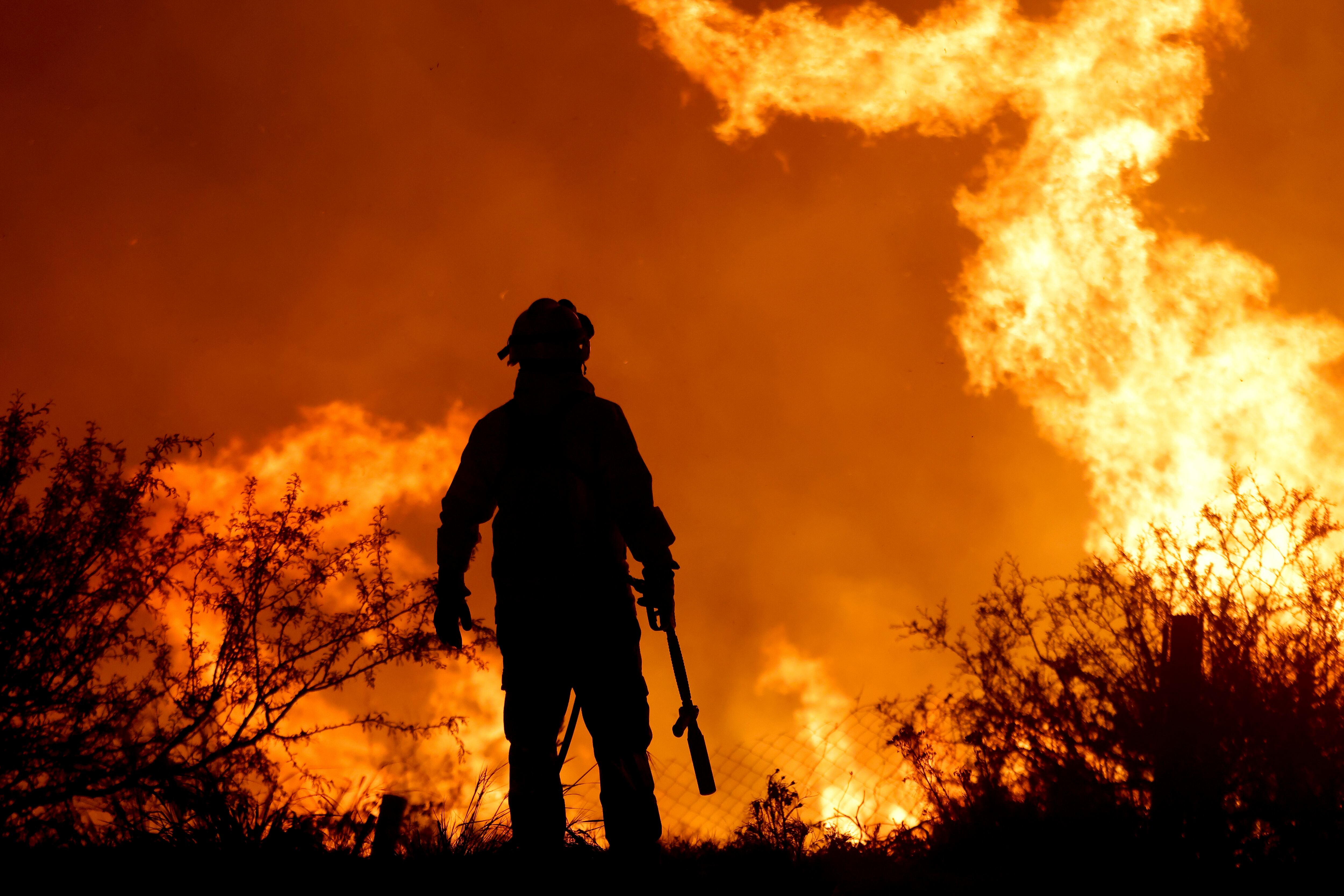 La silueta de un bombero contrasta con las llamas de un incendio forestal, el martes 10 de octubre de 2023, a las afueras de Villa Carlos Paz, Argentina. (AP Foto/Nicolas Aguilera)