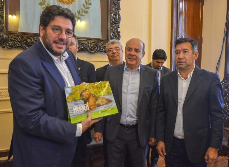 Gustavo Canteros y Gabriel Romero entregaron a Pablo Avelluto un libro sobre los Esteros del Iberá.