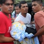 Men carry a woman who collapsed while grieving for a relative who died after an earthquake in Pidie Jaya, Aceh province on December 7, 2016. 
The death toll from a strong 6.5-magnitude earthquake that struck Indonesia's Aceh province on December 7 has nearly doubled to 97, a military chief said. / AFP PHOTO / CHAIDEER MAHYUDDIN