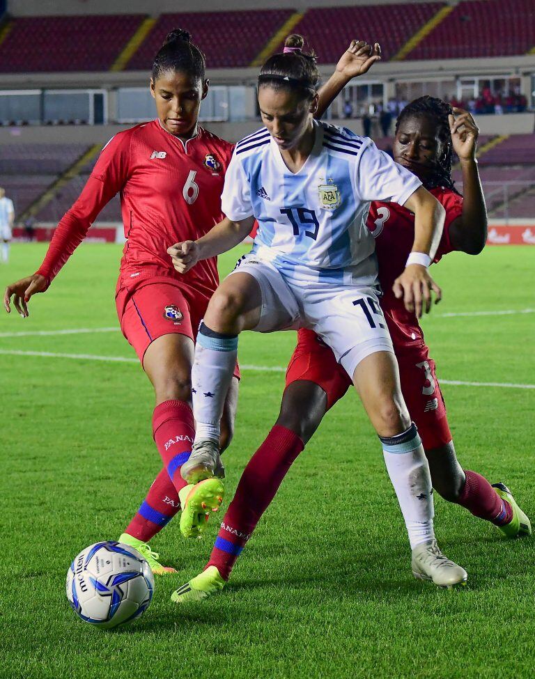 Milagros Otazú con la camiseta de la Selección Argentina de Fútbol Femenino luchando contra dos jugadoras de Panamá en la clasificación para la Women's World Cup 2019. (Foto de Luis ACOSTA / AFP)