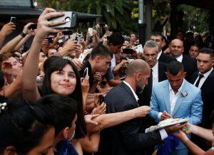 A fan takes a selfie as soccer idol Carlos Tevez signs autographs outside the church where he married Vanesa Mansilla in Buenos Aires, Argentina, Thursday, Dec. 22, 2016. The Boca Juniors player is negotiating his transfer to China's Shanghai Shenhua team