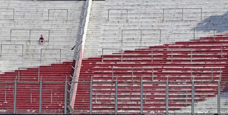 Un hincha de River sentado en soledad en la tribuna del Monumental, luego de que se anunciara que el partido había sido postergado. (Foto: AFP)