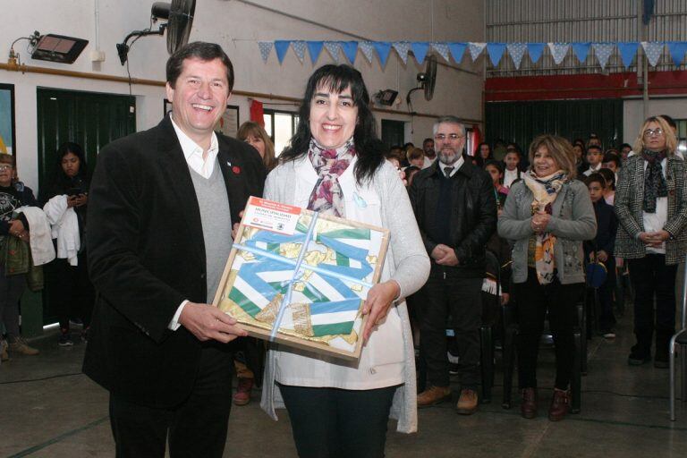 El Intendente Mauricio Cravero entrega la bandera oficial de Arroyito a la Directora Mariela Garelli.