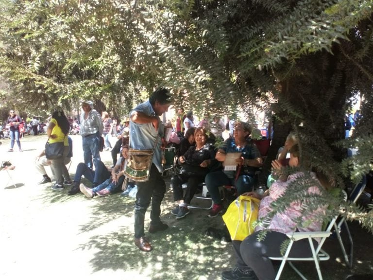 La gente se acomodó a la sombra de los árboles de la plaza, con sombrillas y paraguas debido al agobiante calor. (VíaSalta)