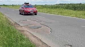 Los vehículos deben transponer su carril para desviar los pozos en una vía de dos sentidos.