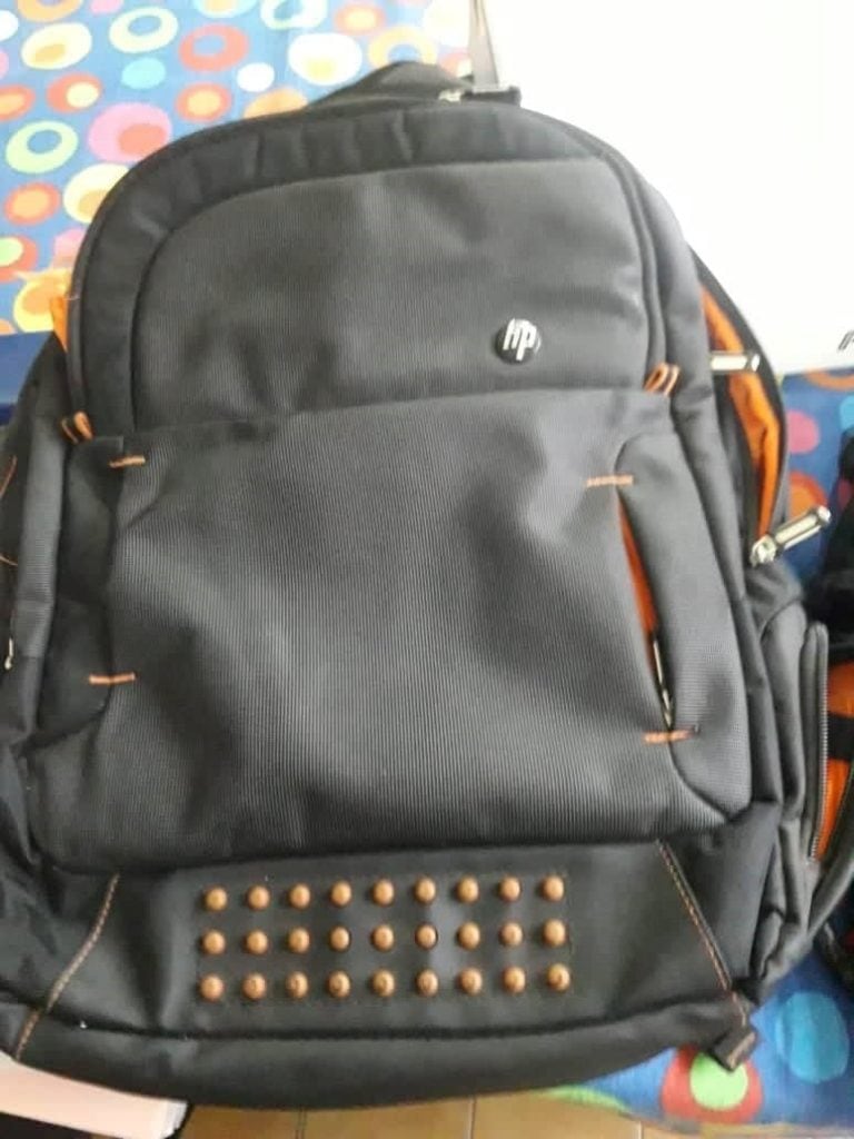 Mochila marca HP de color gris con ribetes naranjas.