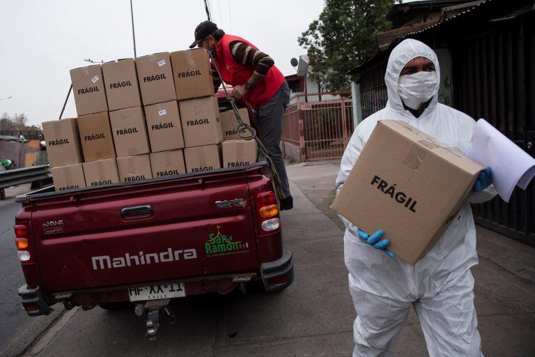 Trabajadores municipales de la comuna de San Ramón reparten cajas con alimentos básicos a familias vulnerables afectadas por las consecuencias de la cuarentena obligatoria decretada para detener el avance de la COVID-19 en Santiago (Chile).EFE/ Alberto Valdés