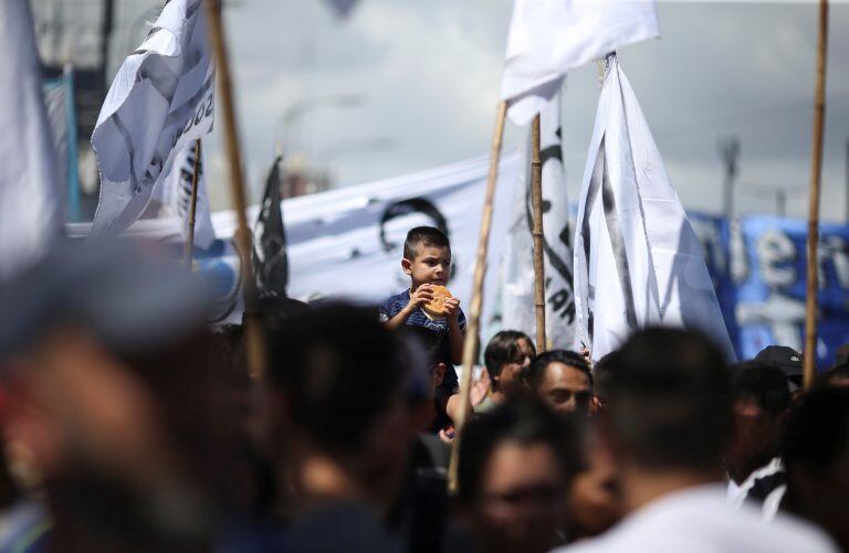 BAS10. BUENOS AIRES (ARGENTINA), 21/02/2018.- Un niño se come una hamburguesa mientras miles de personas participan hoy, miércoles 21 de febrero de 2018, en una marcha por la Avenida 9 de Julio de Buenos Aires (Argentina), convocada por el sindicato de Camioneros de Argentina, a la que se adhieren otros gremios y organizaciones, para protestar contra la gestión del Gobierno que ha generado polémica por las voces que acusan al líder del gremio, Hugo Moyano, de convocarla en su propio beneficio. EFE/David Fernández