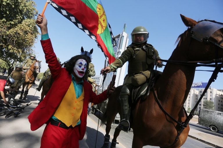 Un grupo de personas se enfrenta a la policía antidisturbios, este viernes, en la Plaza Italia en Santiago de Chile durante una nueva jornada de protestas en contra del gobierno del presidente Sebastián Piñera. (Foto: EFE/ Elvis González)