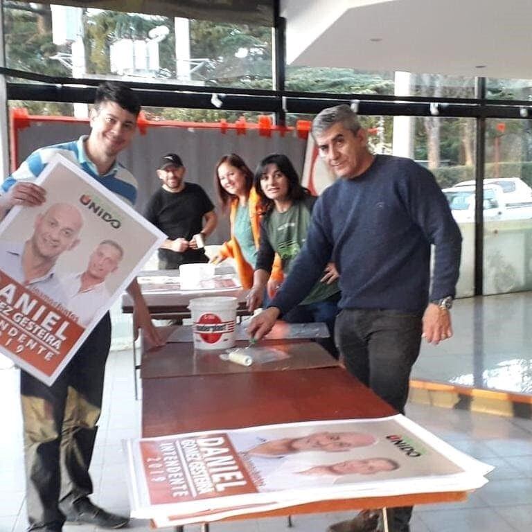 Pare del equipo partidario posando con carteles en mano. (Foto: Facebook).