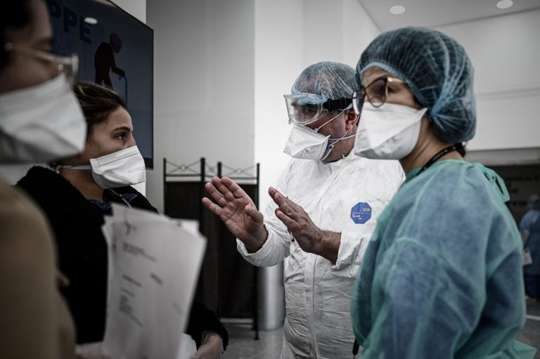 Two women listen to staff members of a medical center testing patient for the COVID-19 virus in Paris on March 27, 2020 during a strict lockdown in France aimed at curbing the spread of the COVID-19 infection, caused by the novel coronavirus. (Photo by Philippe LOPEZ / AFP)