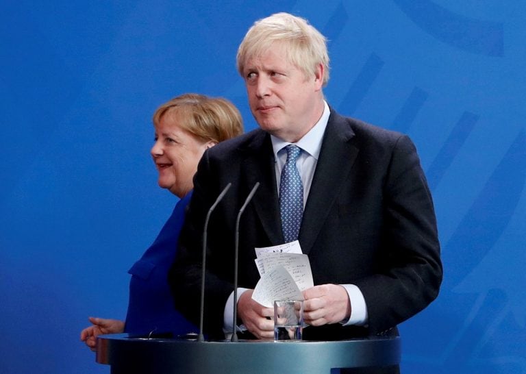 Britain's Prime Minister Boris Johnson holds his notes as he attends a news conference with German Chancellor Angela Merkel at the Chancellery in Berlin, Germany.