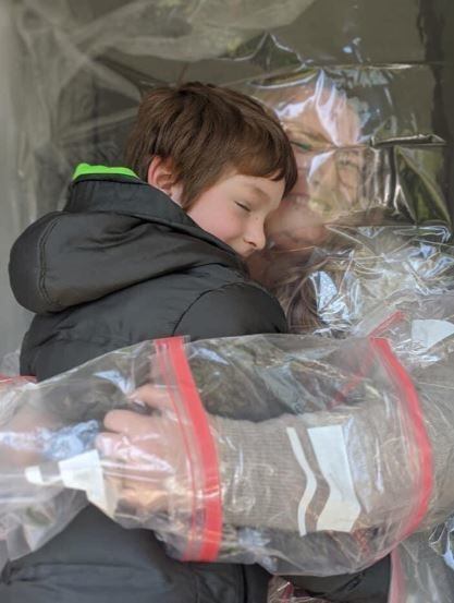 La maestra usó 12 bolsas de residuos para crear una barrera de plástico que le permitiera abrazar a sus alumnos.