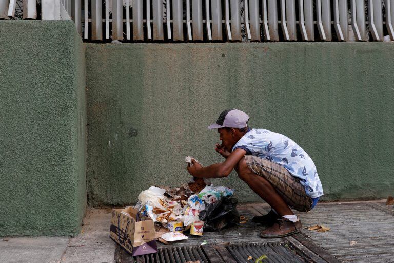 Un hombre come de la basura en una calle de Caracas, Venezuela, en febrero de 2019 (REUTERS)