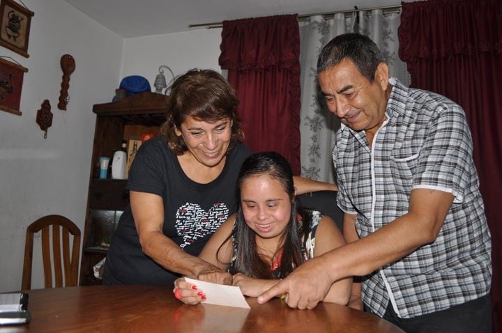 Meli con sus padres mirando fotos.