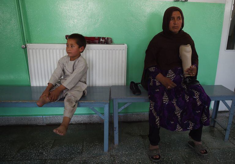 Sayed Ahmad Rahman junto a su madre Bibi Saera Raisa, que sostiene su nueva prótesis (AFP)