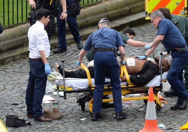 A man is treated by emergency services, as knives lie on the floor, with police looking on at the scene outside the Houses of Parliament London, Wednesday, March 22, 2017.  London police say they are treating a gun and knife incident at Britain's Parliame