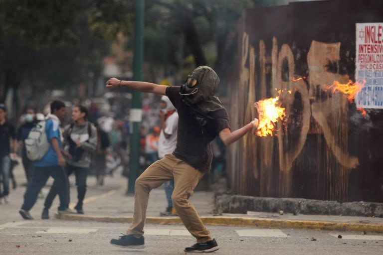 A demonstrator throws a molotov cocktail during clashes with riot police while rallying against Venezuela's President Nicolas Maduro in Caracas, Venezuela, April 20, 2017. REUTERS/Christian Veron