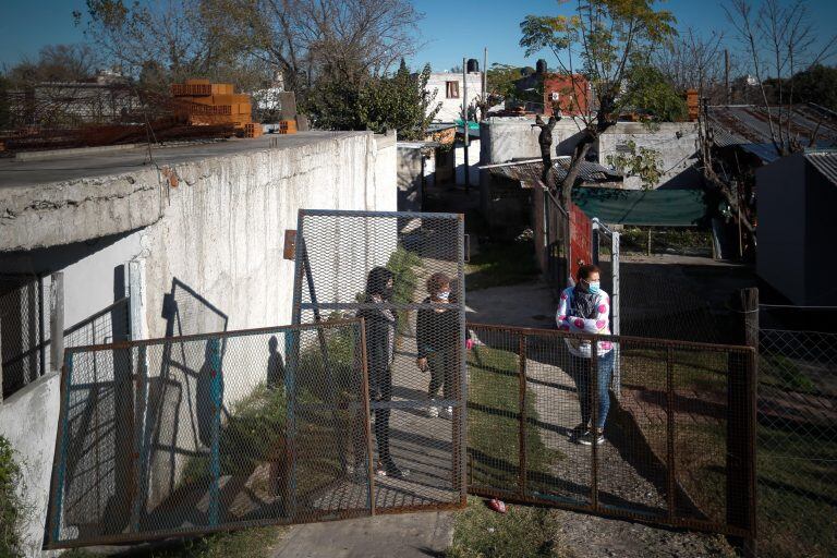 Fotografía a tres mujeres tras una reja este miércoles, en un ingreso a la Villa Azul, la cual se encuentra cerrada para el ingreso y egreso de personas luego de detectar numerosos casos de covid-19, en Buenos Aires (Argentina). (Foto: EFE/Juan Ignacio Roncoroni)