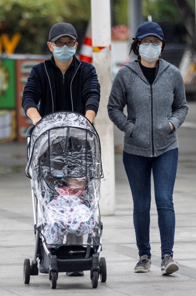 Una pareja pasea con su bebé, protegidos del coronavirus, en Guangzhou, China (EFE)