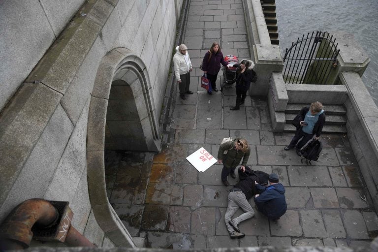 An injured man is assisted on the footpath under Westminster Bridge after an incident in London, Britain March 22, 2017.  REUTERS/Toby Melville