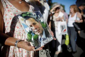 A person holds a photo of late prosecutor Alberto Nisman during a demonstration on the second-year anniversary of his death in Buenos Aires, Argentina, Wednesday, Jan. 18, 2017. Nisman was found dead in the bathroom of his  apartment on this date last yea