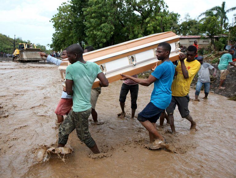 HAI01. PETIT GOAVE (HAITI), 05/10/16.- Varios hombres cargan un ataúd e intentan cruzar el río La Digue, debido al derrumbe del único puente que conecta con el sur, tras el paso del huracán Matthew hoy, 5 de octubre de 2016, en Petit Goave (Haití). El imp