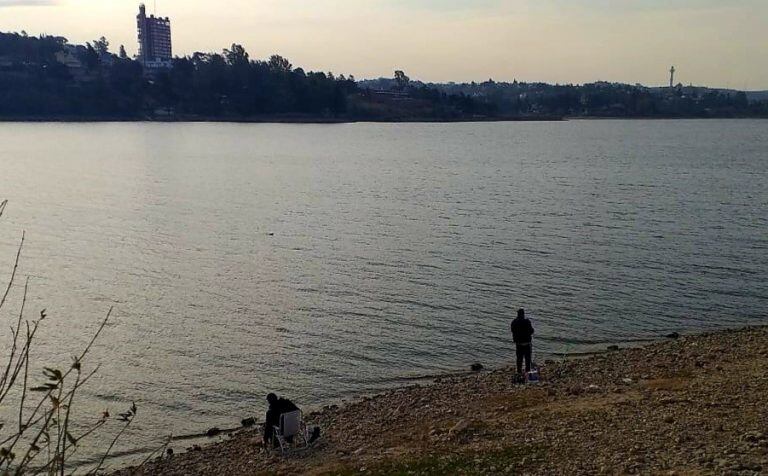 Personas pescando en la costanera de Villa Carlos Paz. (Foto: VíaCarlosPaz).