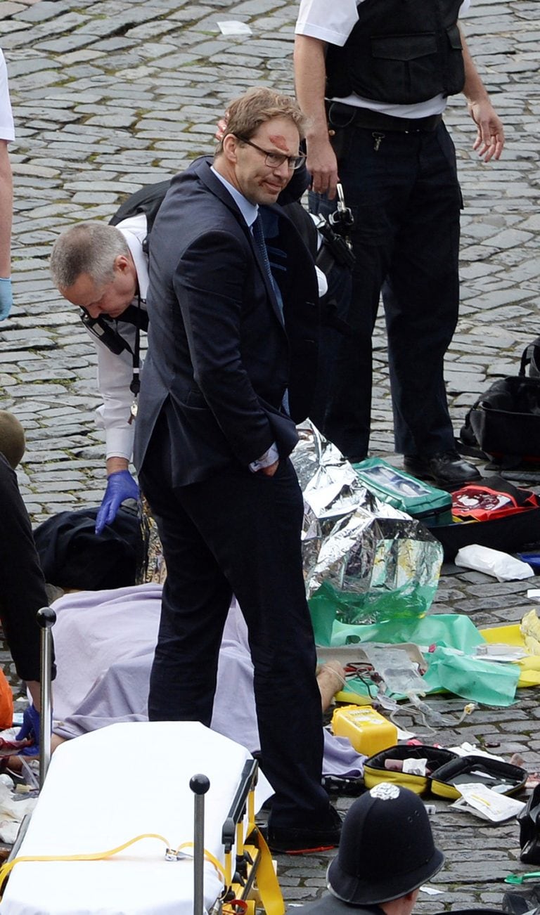 Conservative MP Tobias Ellwood, centre, stands amongst the emergency services at the scene outside the Palace of Westminster, London, Wednesday, March 22, 2017.  London police say they are treating a gun and knife incident at Britain's Parliament "as a te