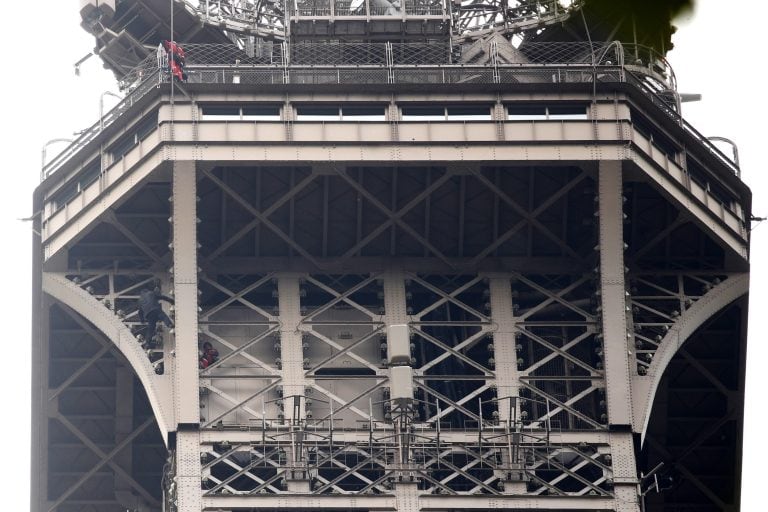 Un hombre escala la Torre Eiffel mientras varios bomberos tratan de detenerlo. (EFE)