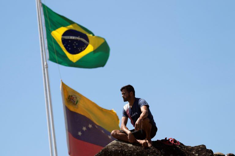 AME7796. PACARAIMA (BRASIL), 23/02/2019.- Vista este sábado de una persona sentada en una pierda en la localidad de Pacaraima, en el límite fronterizo entre Brasil y Venezuela, cerrado desde el jueves por orden del Gobierno de Nicolás Maduro. La primera de las dos grandes camionetas cargadas con parte de la ayuda humanitaria de Brasil para Venezuela llegó este sábado a la localidad Pacaraima. EFE/Joédson Alves