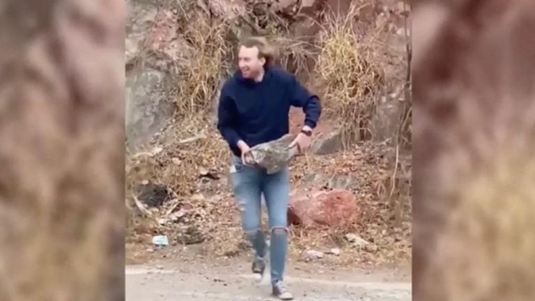 Imagen del joven tomando una piedra de gran tamaño, la misma que lanzó al embudo del Dique San Roque.