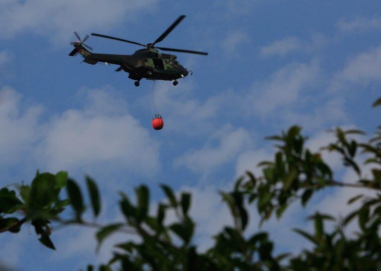 Un helicóptero militar lleva agua para sofocar un punto de incendio, este martes durante una visita del presidente de Bolivia, Evo Morales, en la localidad de Roboré (Bolivia). Crédito: EFE/Martin Alipaz.