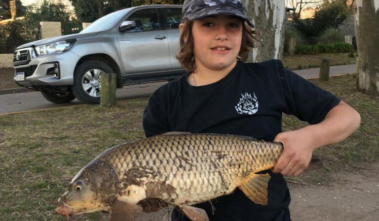 Juancito con la carpa que pescó en el Arroyo Azul.