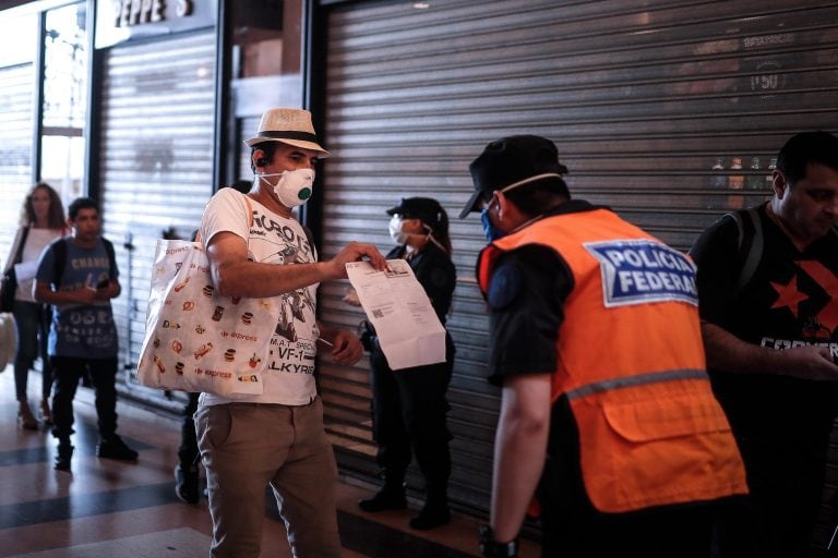 Un hombre le muestra a la policía un certificado para poder circular libremente en la Estación Ferroviaria de Constitución (Foto: EFE/ Juan Ignacio Roncoroni)