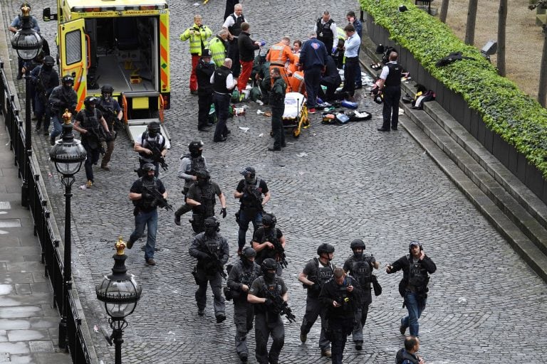 Armed police walk past emergency services attending to injured people on the floor outside the Houses of Parliament, London, Wednesday, March 22, 2017.  London police say they are treating a gun and knife incident at Britain's Parliament "as a terrorist i