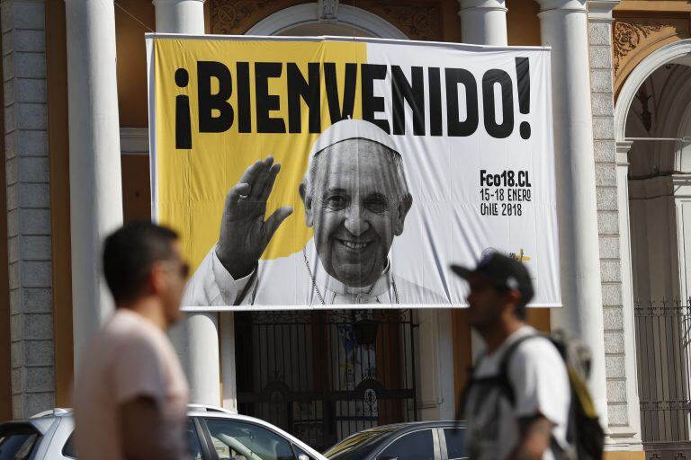 Transeúntes caminan por delante de un cartel de bienvenida al papa Francisco que cuelga en la fachada de la iglesia Divina Providencia el 11/01/2018 en Santiago de Chile, Chile. En su sexto viaje a América Latina, entre el 15 y el 21 de enero, el papa Francisco se encontrará en Chile una Iglesia católica cuestionada y alejada de la gente, mientras que Perú lo recibirá en medio de una gran tensión política a raíz del indulto presidencial al ex mandatario Alberto Fujimori.  (Vinculado al texto de dpa "Una Iglesia cuestionada en Chile y tensión en Perú recibirán al papa" del 12/01/2018). foto: Francisco Flores Seguel/Agencia Uno/dpa