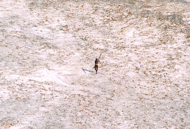 Un hombre tribal  apunta con su arco y flecha a un helicóptero de la Guardia Costera de la India mientras vuela sobre la isla para un estudio de los daños causados ​​por el tsunami en el archipiélago indio de Andaman y Nicobar. Crédito: REUTERS/Indian Coast Guard.