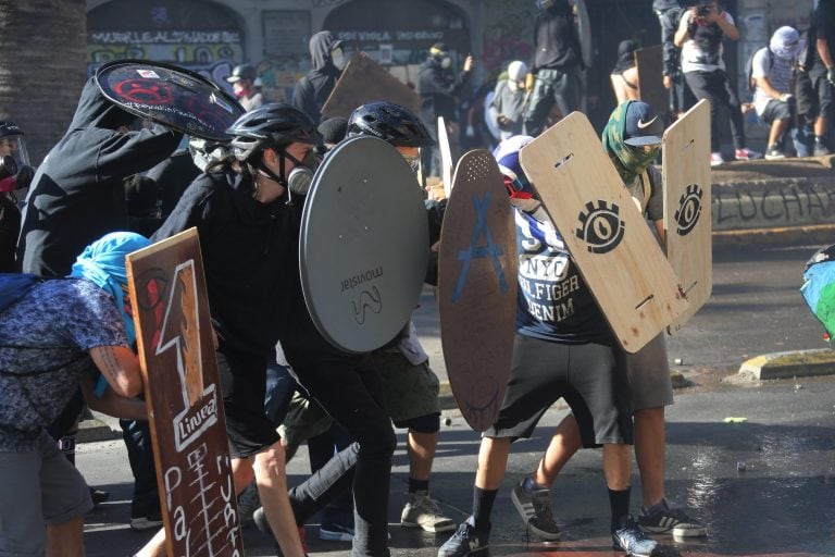 Un grupo de personas se enfrenta a la policía antidisturbios, este viernes, en la Plaza Italia en Santiago de Chile durante una nueva jornada de protestas en contra del gobierno del presidente Sebastián Piñera. (Foto: EFE/ Elvis González)