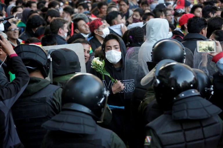 Un manifestante sostiene flores mientras está parado frente a la policía durante una protesta en La Paz, Bolivia, el 22 de octubre de 2019. Crédito: REUTERS / David Mercado.