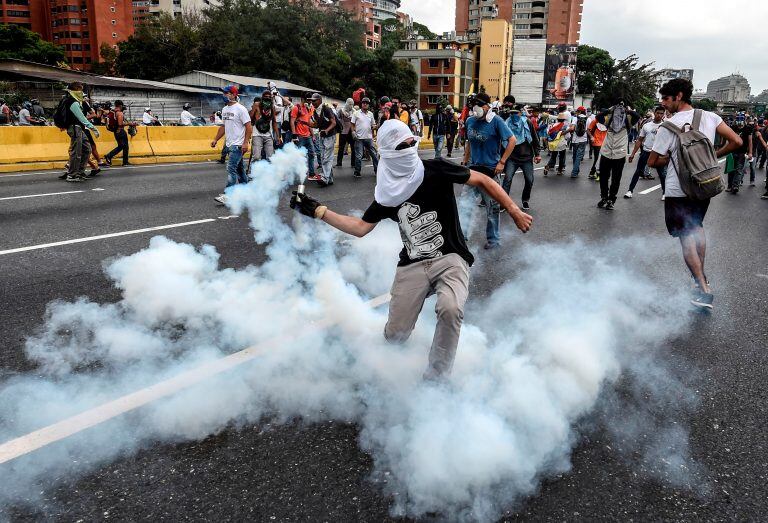 Demonstrators clash with the riot police during a protest against Venezuelan President Nicolas Maduro, in Caracas on April 20, 2017.
Venezuelan riot police fired tear gas Thursday at groups of protesters seeking to oust President Nicolas Maduro, who have vowed new mass marches after a day of deadly unrest. Police in western Caracas broke up scores of opposition protesters trying to join a larger march, though there was no immediate repeat of Wednesday's violent clashes, which left three people dead. / AFP PHOTO / JUAN BARRETO