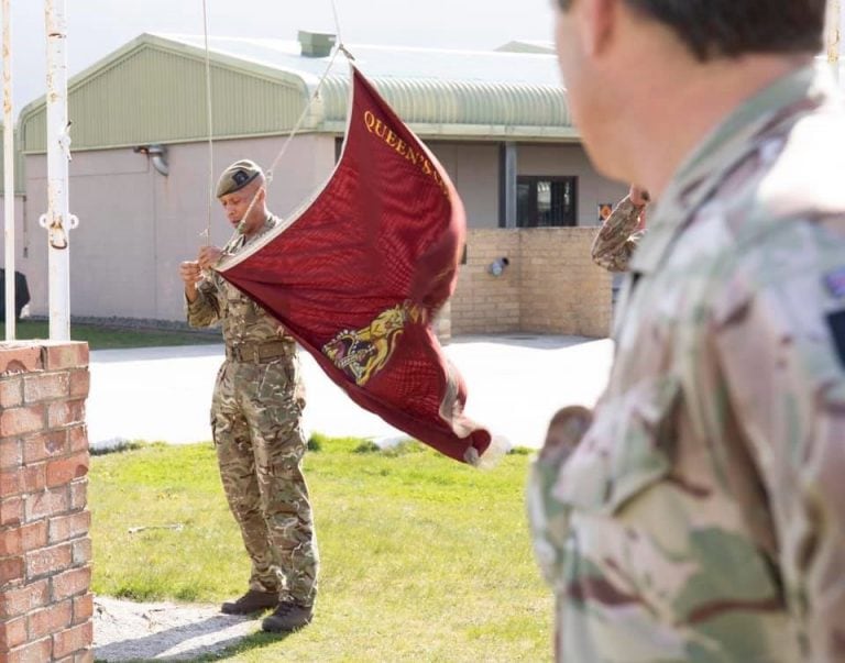 Un soldado de la Compañía de la Reina coloca la bandera de su guarnición para ser izada en el mástil de las instalaciones de RIC.