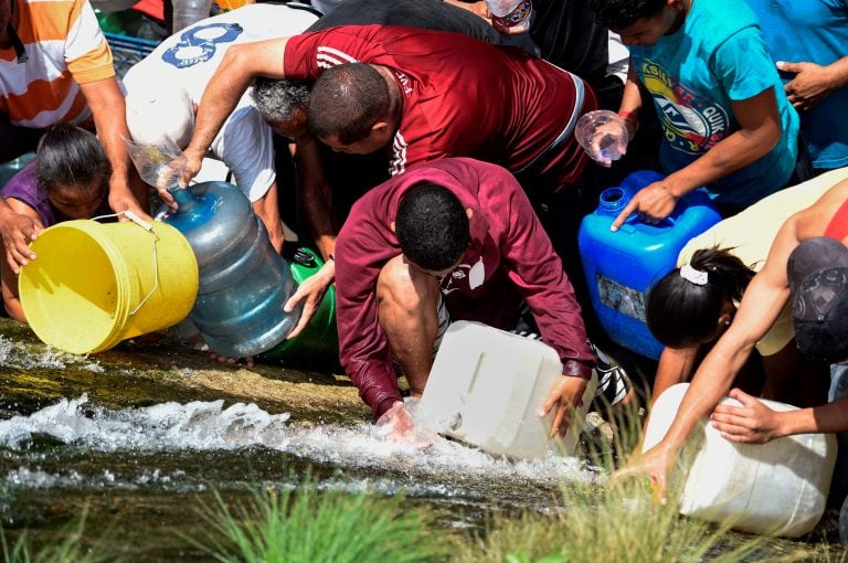 La gente recoge agua de donde puede, aquí desde un canal del río Guaire