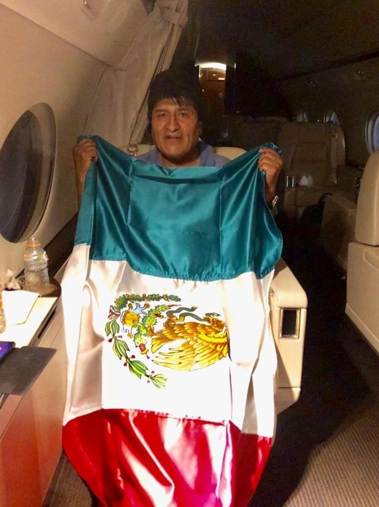 El expresidente de Bolivia, Evo Morales, posa con una bandera mexicana, durante su viaje en un avión de la Fuerza Aérea Mexicana. Crédito: EFE/ Cancillería De México.