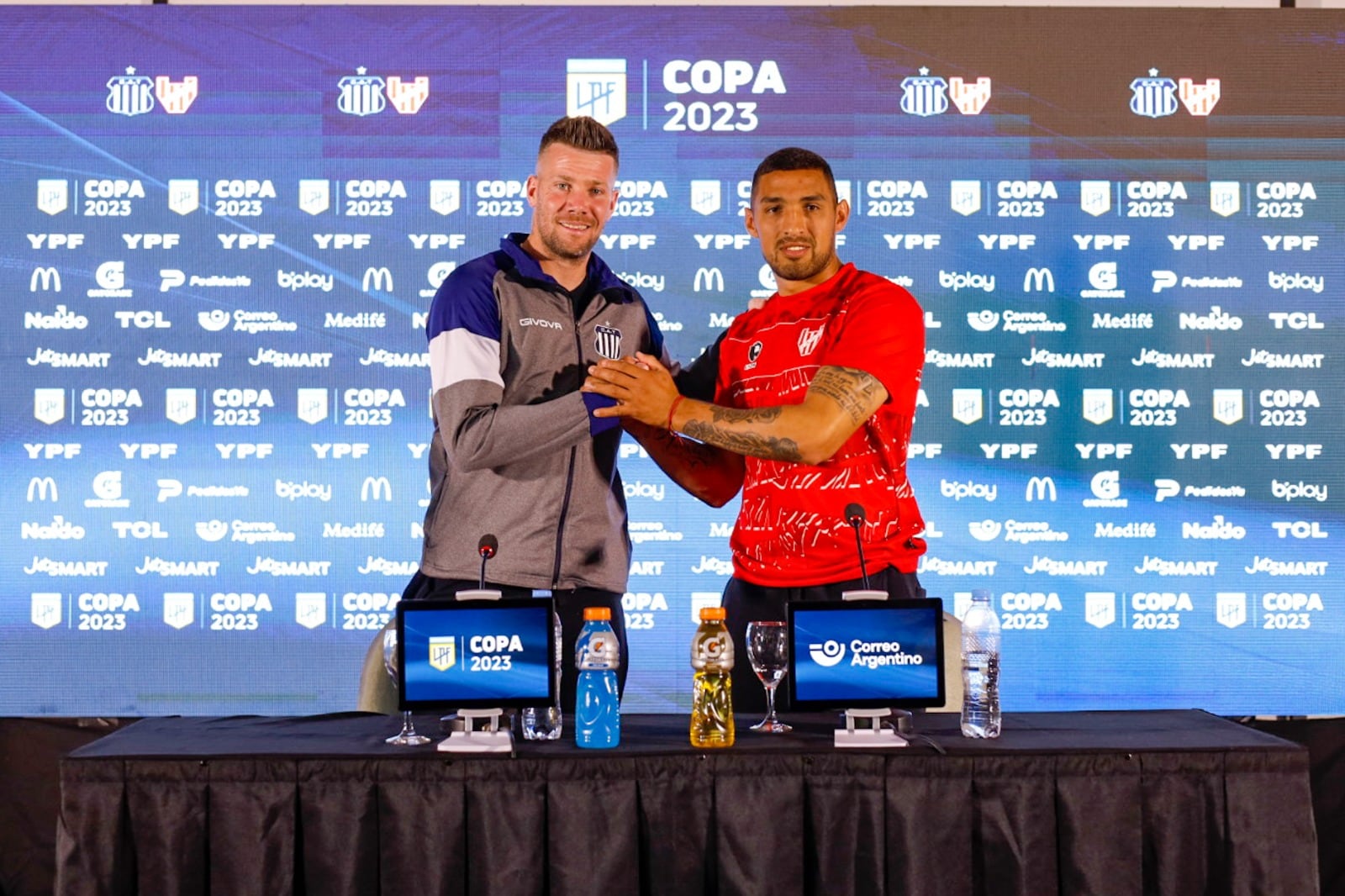 Guido Herrera y Fernando Alarcón se saludan en la conferencia de prensa previa al clásico entre Talleres e Instituto