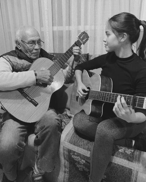 Emilia Mernes tocando la guitarra junto a su abuelo