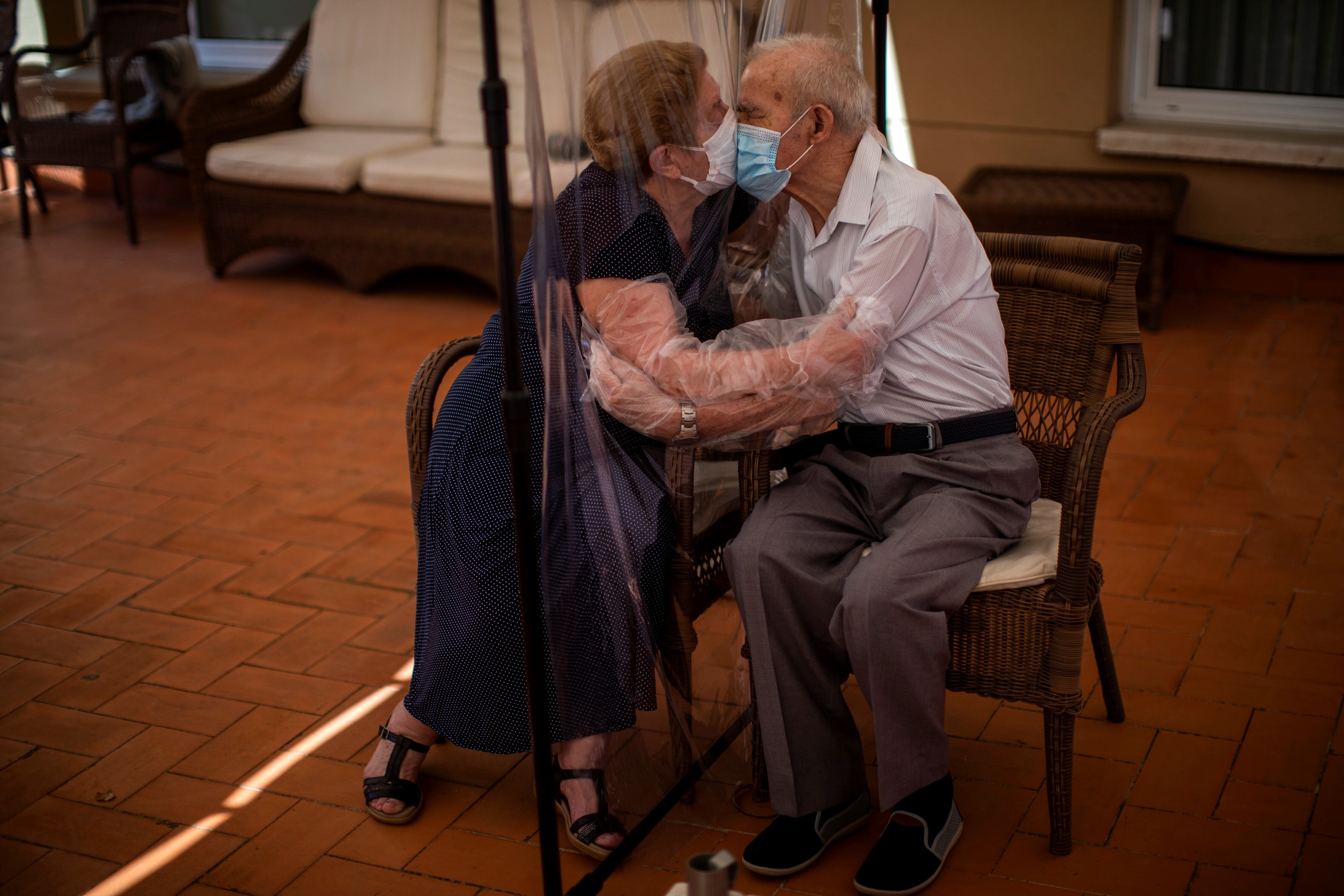 Agustina Canamero, de 81 años, y Pascual Pérez, de 84, se abrazan y besan a través de una cortina de plástico para evitar contraer el nuevo coronavirus en una residencia de adultos mayores en Barcelona. Foto Emilio Morenatti 