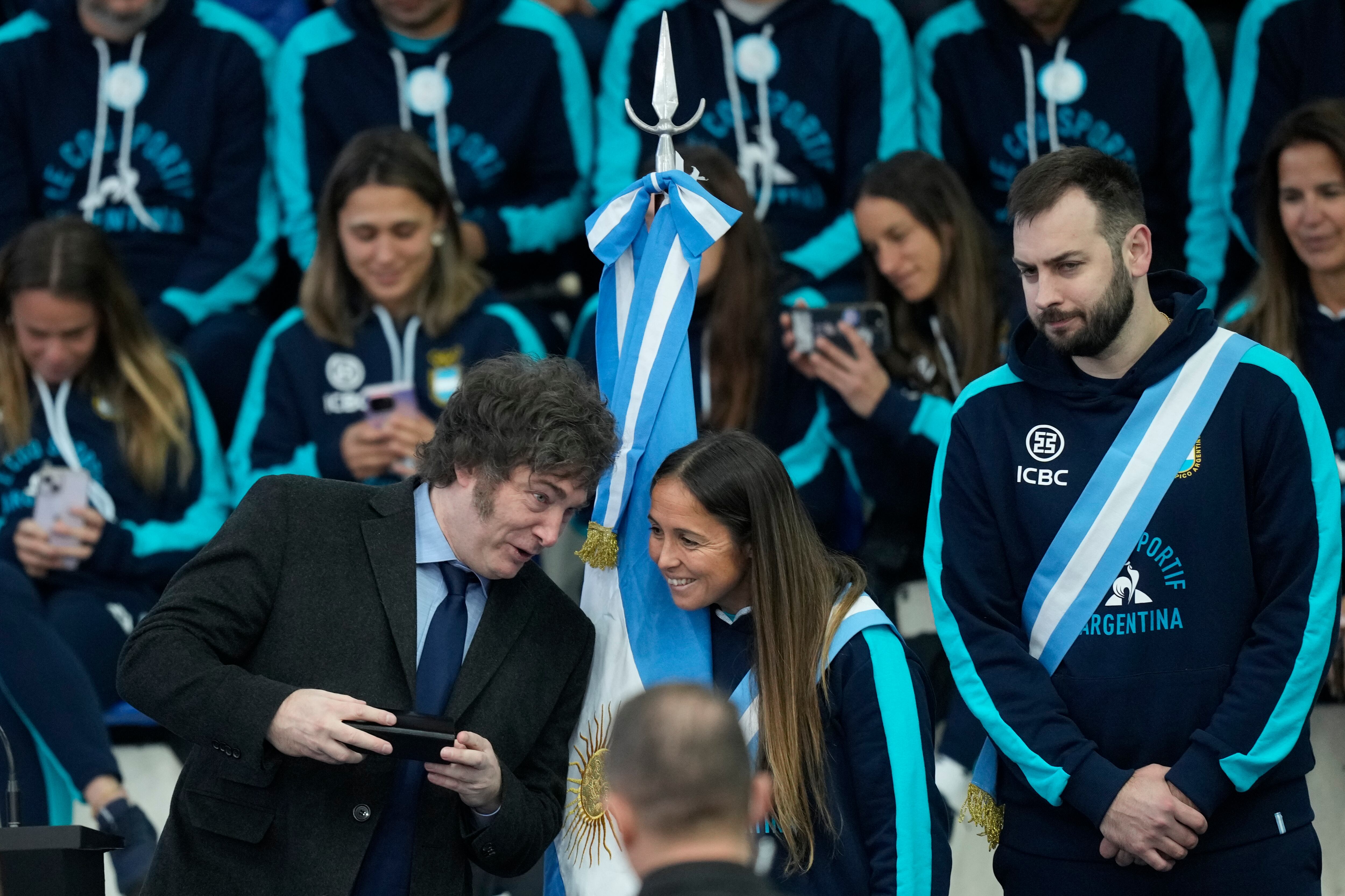 El presidente argentino Javier Mieli, a la izquierda, habla con la jugadora de hockey sobre césped Rocío Sánchez Moccia y el jugador de vóleibol Luciano De Cecco durante la ceremonia de despedida de los atletas argentinos que competirán en los Juegos Olímpicos de París, en Buenos Aires, Argentina, viernes 5 de julio, 2024. (AP Foto/Natacha Pisarenko)